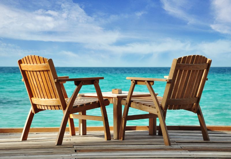 שני כיסאות עץ על מרפסת מול הים